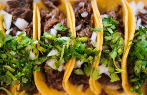 A close-up photo of a mouthwatering beef recipe, featuring seasoned ground beef, topped with fresh ingredients and nestled in a warm tortilla